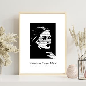 Puede incluir: Una impresión artística en blanco y negro enmarcada con un retrato estilizado de Adele. El retrato está lleno de texto y sobre un fondo negro. La impresión está etiquetada como "Hometown Glory - Adele".