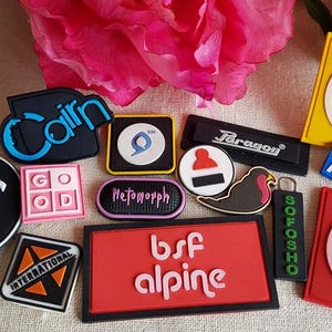 以下が含まれることがあります： さまざまな形と色のパッチのコレクションです。「Cairn」、「bsf alpine」、「PESCA」などのテキストが書かれたパッチがあります。鳥や様式化されたワシなど、グラフィックデザインが施されたパッチもあります。