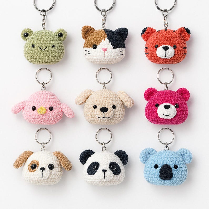 May include: Nine crochet animal keyrings, including a green frog, a calico cat, a red tiger, a pink bird, a beige dog, a fuchsia bear, a white and brown dog, a panda, and a blue koala. Each keyring has a silver metal ring.