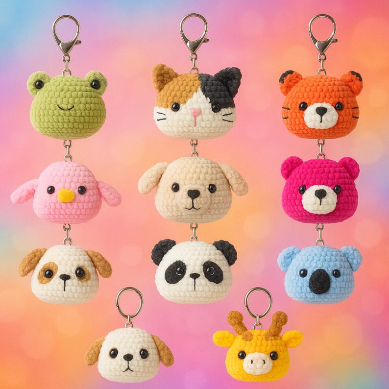 May include: A selection of handmade crochet keyrings in the shape of animal faces. The keyrings include a green frog, a calico cat, an orange tiger, a pink bird, a tan dog, a pink bear, a panda, a koala, a brown and white dog, and a yellow giraffe.