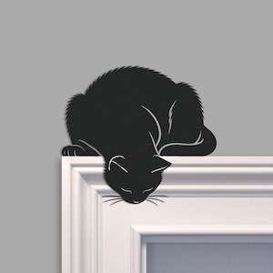Puede incluir: Silueta negra de un gato acurrucado y descansando sobre una repisa blanca. La cabeza del gato cuelga hacia abajo, con los ojos cerrados y los bigotes visibles. El fondo es de color gris sólido.