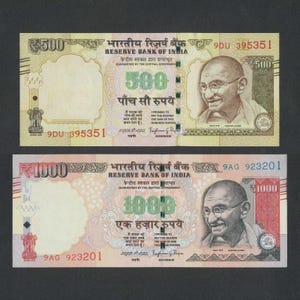 May include: Two Indian banknotes: a ₹500 note and a ₹1000 note. The ₹500 note is light green and features a portrait of Mahatma Gandhi. The ₹1000 note is a darker shade and also features Gandhi. Both notes have text in English and Hindi.