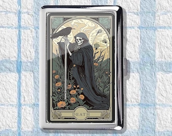 Op de afbeelding: Een zilveren sigarettenetui met een tarotkaartontwerp. De kaart toont de Grim Reaper in een zwarte mantel, met een staf, met een raaf erop. Het woord "DEATH" staat onderaan de kaart.