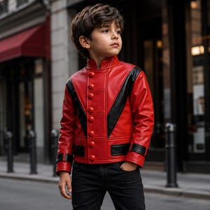 May include: A red leather jacket featuring black V-shaped panels on the chest, a high collar, and a vertical row of round red buttons. The sleeves have black cuffs with straps, and the jacket is worn with black trousers in an urban setting.