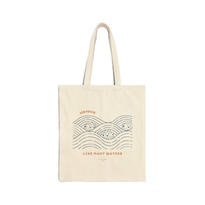 Könnte beinhalten: Cremefarbene Tragetasche mit einem grafischen Wellenmuster in Marineblau und einem rostfarbenen Text mit der Aufschrift "HIS VOICE" und "LIKE MANY WATERS". Die Tasche hat zwei Griffe und besteht aus robustem Stoff.