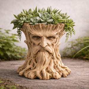 Op de afbeelding: Een gedetailleerde, beige plantenbak in de vorm van een boomstam met een gezicht erin gebeeldhouwd. De plantenbak is gevuld met een verscheidenheid aan groene vetplanten en hangplanten. Het ontwerp roept een mystiek, natuurlijk thema op.