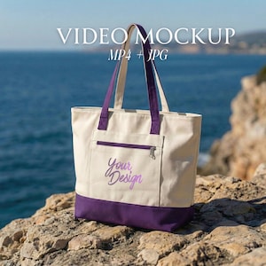 Peut inclure: Un sac fourre-tout en toile crème avec une base et des anses violettes. Le sac possède une poche avant zippée et les mots "Your Design" brodés en violet. L'arrière-plan montre la mer et une surface rocheuse.