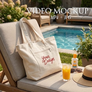 May include: A cream-colored tote bag with a front pocket and zipper, featuring the text "Your Design" in red script. The bag rests on a lounge chair near a pool, with a drink, sunglasses, sunscreen, and a straw hat.