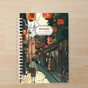 May include: Spiral-bound notebook featuring an illustrated Japanese street scene. The cover art depicts a person walking down a lantern-lit alleyway. The word "Notebook" is displayed in a decorative label. The color palette includes warm oranges, greens, and browns.