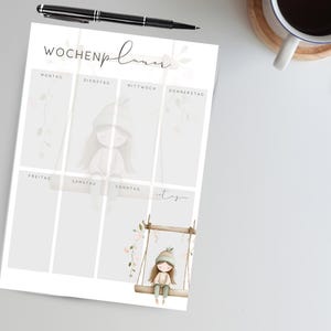 May include: A weekly planner with a soft, neutral color palette. The design features a whimsical illustration of a girl on a swing, with floral accents. The planner includes sections for each day of the week, with the word "Wochenplaner" at the top.