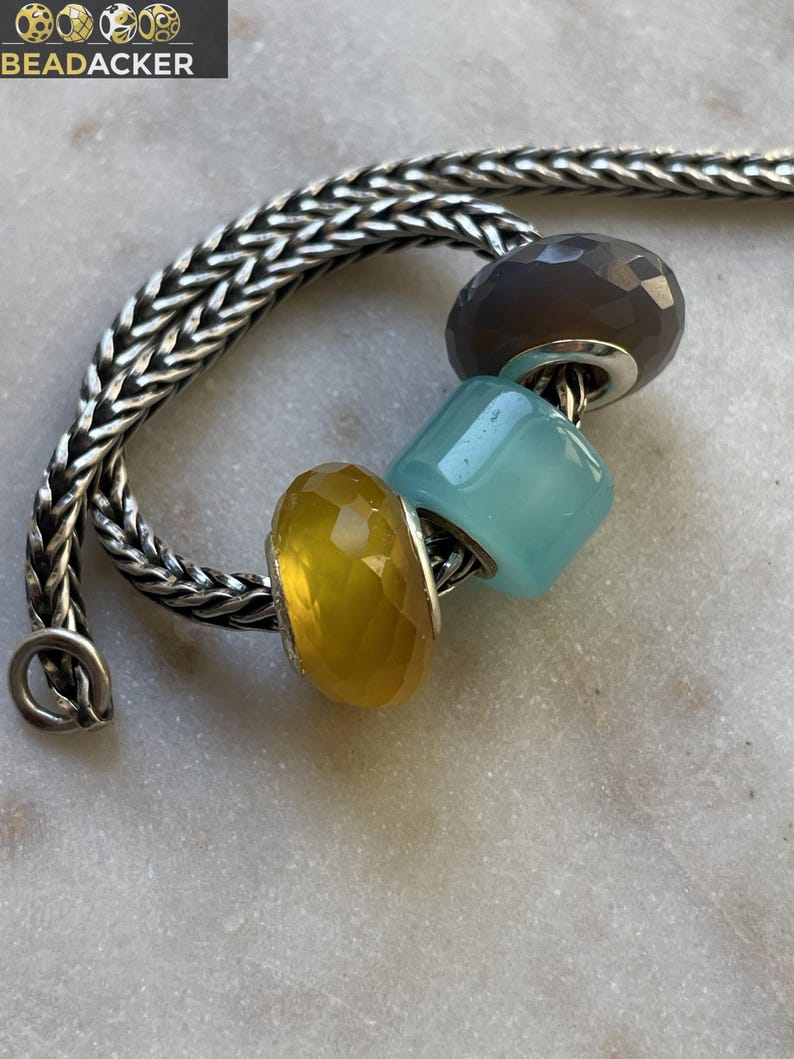 Op de afbeelding: Een set van drie keramische mokken met een gespikkelde, matte afwerking. De mokken zijn in cr&egrave;me, lichtgrijs en donkergrijs. Elke mok heeft een eenvoudig, minimalistisch ontwerp en een afgeronde handgreep.