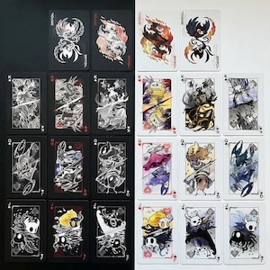 Puede incluir: Una baraja de cartas con ilustraciones únicas de personajes. Las cartas se dividen en dos juegos, uno con fondo negro y otro con fondo blanco. Cada carta muestra un diseño de personaje diferente en varios colores.
