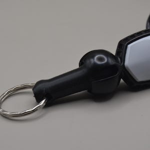 May include: A black and silver lanyard safety key with a coiled cord. The key has a black handle and a silver metal ring. The key has the word "SEADOO" printed on it.