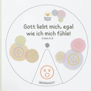 May include: A white circular graphic with German text and colorful smiley face illustrations. The text reads "Gott liebt mich, egal wie ich mich fühle!" and "Überrascht". The graphic has a small metal fastener in the center.