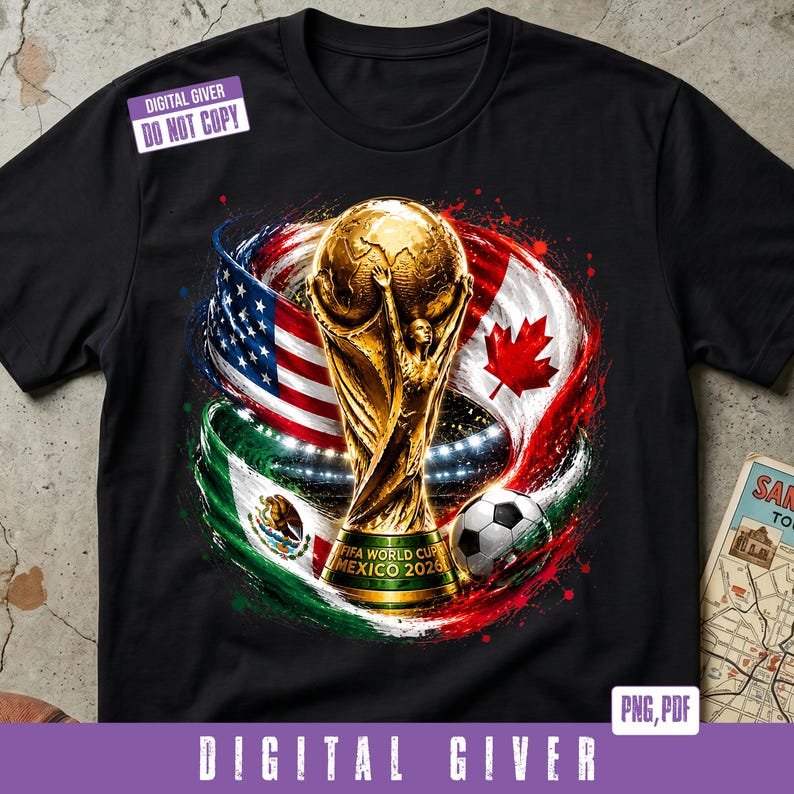 May include: A black t-shirt featuring a graphic of the gold FIFA World Cup trophy, a soccer ball, and the flags of the United States, Canada, and Mexico. The trophy base includes the text FIFA WORLD CUP MEXICO 2026. A digital watermark is present.