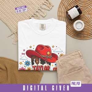 May include: A white t-shirt featuring a graphic of a red cowboy hat with a gold sheriff star, a cow print pattern, and the name Taylor in red letters. The design is surrounded by colorful flowers, small stars, and clouds on a white fabric.
