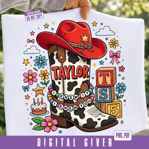 May include: A white graphic print featuring a red cowboy hat atop a cow-print boot. The boot displays the name TAYLOR, a beaded bracelet reading I KNEW IT I KNEW YOU, and is surrounded by colorful flowers, a sheriff star, a cake, and blocks.