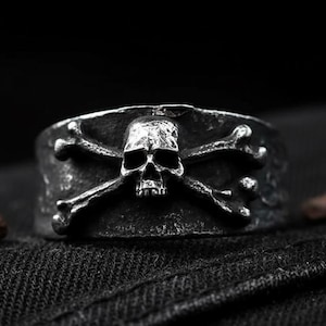 May include: A white ceramic mug with a black handle and the text "But First, Coffee" in a bold, black font. The mug is set against a blurred background, suggesting a cozy setting.