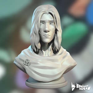 May include: A 3D-printed bust of a person with long hair and a draped garment. The figure has a serene expression and a detailed face. A circular emblem is on the garment. The bust is on a round base. The background is blurred.