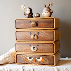 May include: A wooden storage chest with four drawers, each decorated with a different animal face: a bear, an owl, and other cartoon characters. The chest is made of dark wood with a light wood trim. Decorative figurines sit on top.