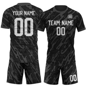 May include: Black and gray athletic uniform set with a camouflage pattern. The jersey features the text "YOUR NAME" and the number "00" on the back, and "TEAM NAME" and "00" on the front. Includes shorts.