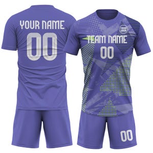 May include: A two-piece athletic uniform in periwinkle blue. The jersey features the text "YOUR NAME" and "TEAM NAME" with the number "00". The shorts also have the number "00". The jersey has a geometric design with a logo.