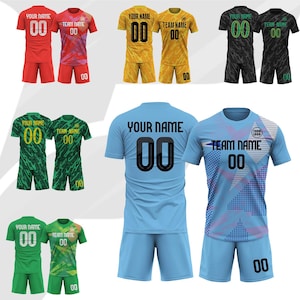 Puede incluir: Una colección de camisetas y pantalones cortos de fútbol en varios colores, incluyendo rojo, amarillo, negro, verde y azul. Cada camiseta presenta un nombre de equipo, un número y elementos de diseño. Las camisetas se muestran sobre un fondo blanco.