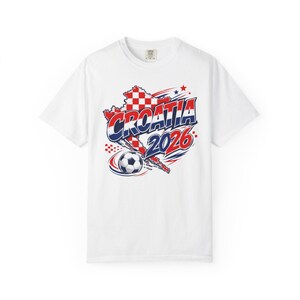 May include: White t-shirt featuring a graphic design with the word "CROATIA" in red and blue, along with the year "2026". The design includes a map outline of Croatia and a soccer ball.