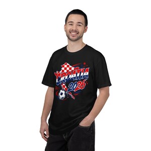 May include: Black t-shirt featuring a graphic design with the word "CROATIA" in red and white, the year "2026" in red and blue, and a soccer ball. The design includes a map of Croatia.