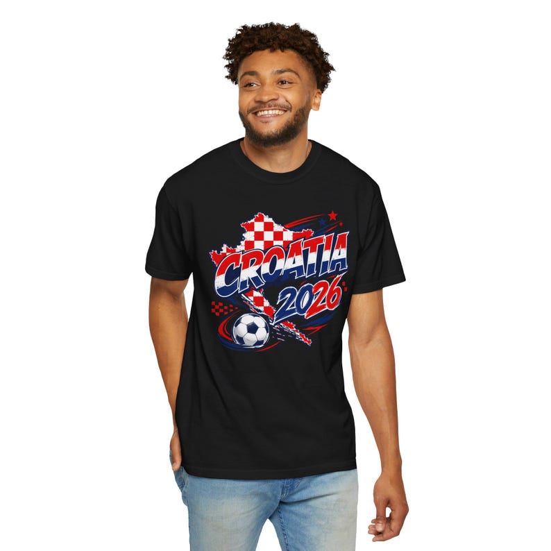 May include: Black t-shirt featuring a graphic design with the text "CROATIA 2026" in red, white, and blue. The design includes a map outline of Croatia and a soccer ball. The shirt is made of a soft material.