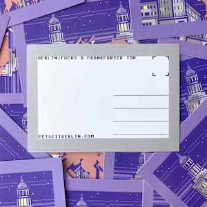 May include: A postcard with the text "BERLIN/FUCHS & FRANKFURTER TOR" and "PETSCIIBERLIN.COM". The postcard is white with gray borders and lines for writing. Surrounding postcards have a purple and orange cityscape design.