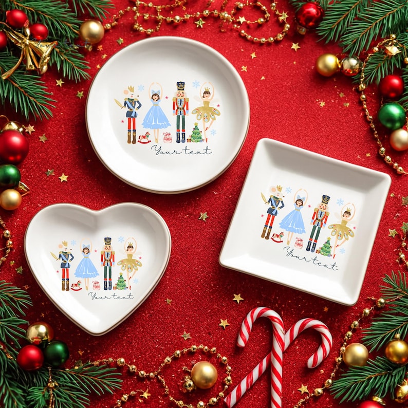 May include: Three white ceramic dishes in round, heart, and square shapes, each with a gold rim and a Nutcracker-themed illustration. The dishes are on a red surface with Christmas decorations, including candy canes and evergreen branches. The text "Your text" is printed on each dish.