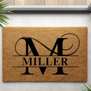 Peut inclure: Un paillasson rectangulaire en fibre de coco naturelle. Il présente un grand "M" noir stylisé au-dessus du nom "MILLER" en caractères gras sans empattement. Un accessoire de bienvenue pour toute entrée.