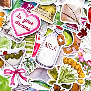 Puede incluir: Una colección de pegatinas coloridas con varios diseños. Incluye una botella de leche con una etiqueta, una copa de martini con aceitunas, una pegatina en forma de corazón con el texto "In your dreams", y diseños florales y de comida.