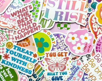 May include: A collection of colorful stickers with various designs and text. The stickers feature phrases like "Still I Rise," "Treat Yourself With Kindness," and "What You Give." The color palette includes pink, green, orange, and blue.