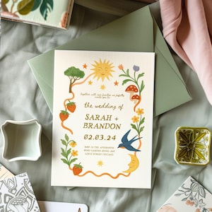 May include: Wedding invitation with a whimsical design featuring a sun, moon, and floral border. The invitation includes the names "SARAH + BRANDON" and the date "02.03.24". The text "the wedding of" is also visible.