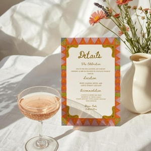May include: A wedding details card with a decorative border and the word "Details" in script. A glass of champagne is in front of the card, and a vase of flowers is in the background.