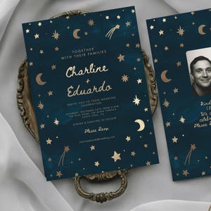 Könnte beinhalten: Dunkelblaue Hochzeitseinladung mit goldenen Sternen, Monden und Text. Die Einladung lautet "Charline + Eduardo" und enthält Details zur Veranstaltung. Die Einladung befindet sich auf einem dekorativen Tablett.