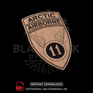 Op de afbeelding: Houten schildvormig embleem met de woorden "ARCTIC AIRBORNE" bovenaan. Daaronder een cirkelvormig embleem met het nummer "11" in het midden, geflankeerd door vleugels. Het embleem is lichtbruin met donkerbruine details. De onderste tekst luidt "DIRECT DOWNLOADEN" en "VOOR PERSOONLIJK EN COMMERCIEEL GEBRUIK".