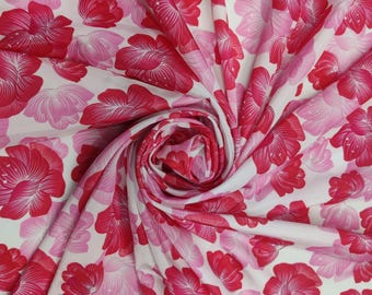 May include: A fabric with a repeating floral pattern in shades of pink and red on a white background. The flowers are stylized and arranged in a dense, all-over design. The fabric is gathered, creating folds and shadows.