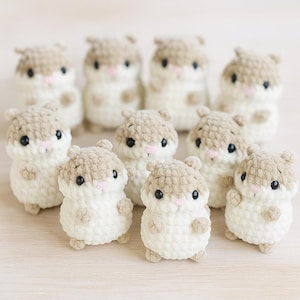 Könnte beinhalten: Eine Sammlung handgefertigter Häkel-Hamster-Plüschtiere. Jedes Plüschtier hat einen cremefarbenen Körper, einen hellbraunen Kopf und kleine schwarze Augen. Die Hamster haben rosa Nasen und winzige Arme und Füße. Die Plüschtiere sind in einer Gruppe angeordnet.