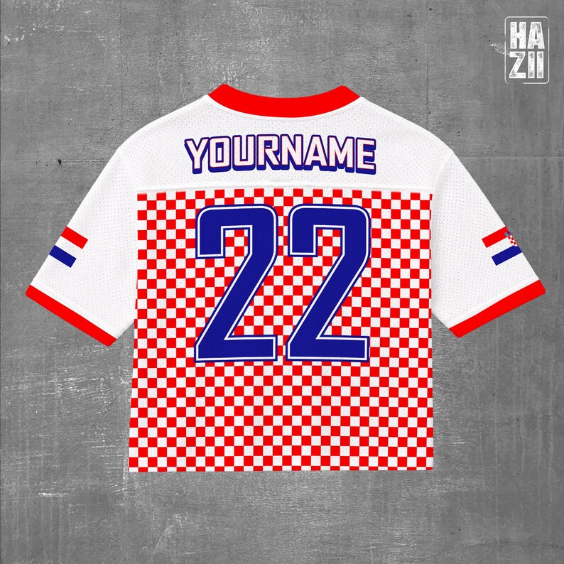 May include: A white short-sleeved jersey featuring a red and white checkered pattern on the lower half. The back displays the text YOURNAME in blue and the number 22 in large blue digits. The sleeves have red trim and a small Croatian flag emblem.