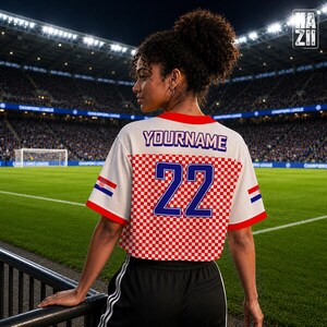 May include: A white short-sleeved jersey featuring a red and white checkered pattern on the lower half, the text YOURNAME in blue, and the number 22 in blue. The sleeves have red trim and a small Croatian flag emblem on each side of the jersey.