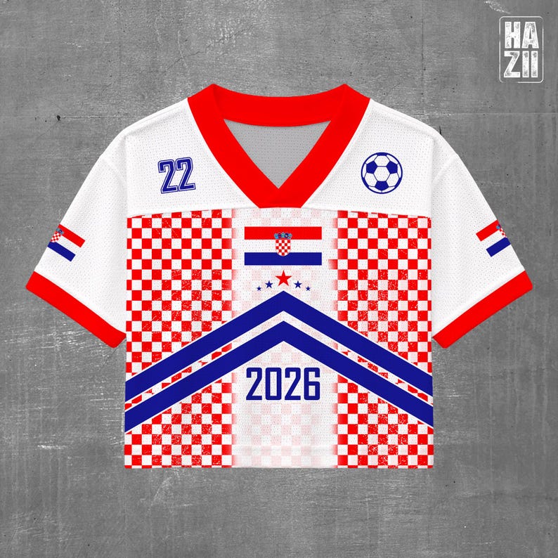 May include: A white short-sleeve jersey with a red V-neck collar and red sleeve cuffs. The front features a red and white checkered pattern, a blue chevron design, the number 22, a soccer ball icon, the Croatian flag, and the text 2026.