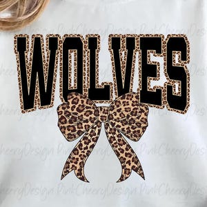 May include: White sweatshirt with the word "WOLVES" in black block letters with a leopard print fill. A leopard print bow is centered below the word. The sweatshirt is a casual style.