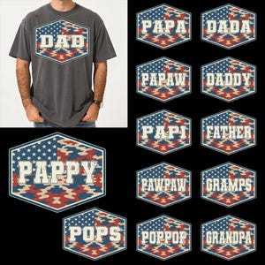 May include: Dark gray t-shirt with a distressed "DAD" graphic in a patriotic design. The graphic is a hexagon shape with a blue and white stars and stripes pattern, and a red, white, and blue camouflage pattern. Additional graphics with various "Dad" titles.