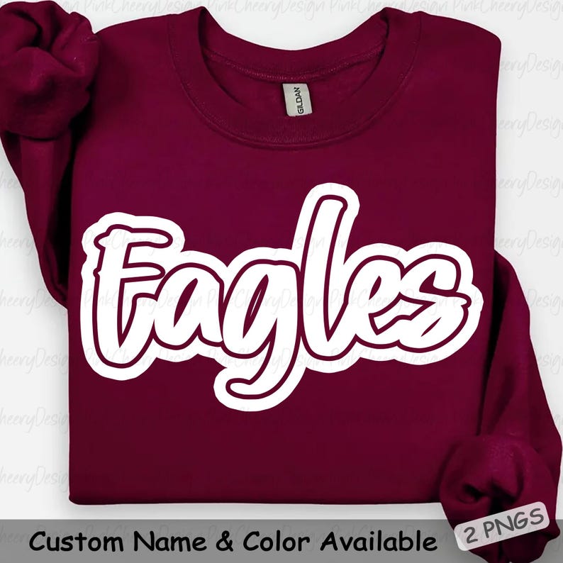 May include: A maroon sweatshirt with the word "Eagles" in a white, outlined script font. The sweatshirt has long sleeves and a crew neck. The text "Custom Name & Color Available" is at the bottom.