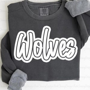 May include: A dark gray sweatshirt with the word "Wolves" in large, white, cursive lettering. The sweatshirt has a crew neck and long sleeves with gray, fuzzy cuffs. The Comfort Colors tag is visible.