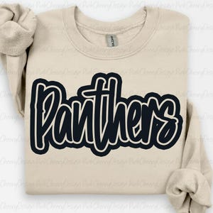 Peut inclure: Un sweat-shirt beige avec le mot "Panthers" en bleu marine, souligné de blanc. Le sweat-shirt a un col rond et des manches longues. L'étiquette de la marque Gildan est visible à l'intérieur du col.
