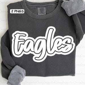 May include: A dark gray sweatshirt with the word "Eagles" in large, white, outlined letters across the front. The sweatshirt has long sleeves and a crew neck. The text "2 PNGS" is in the upper left corner.